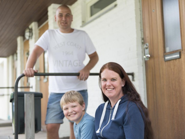 En leende familj sitter i trappan